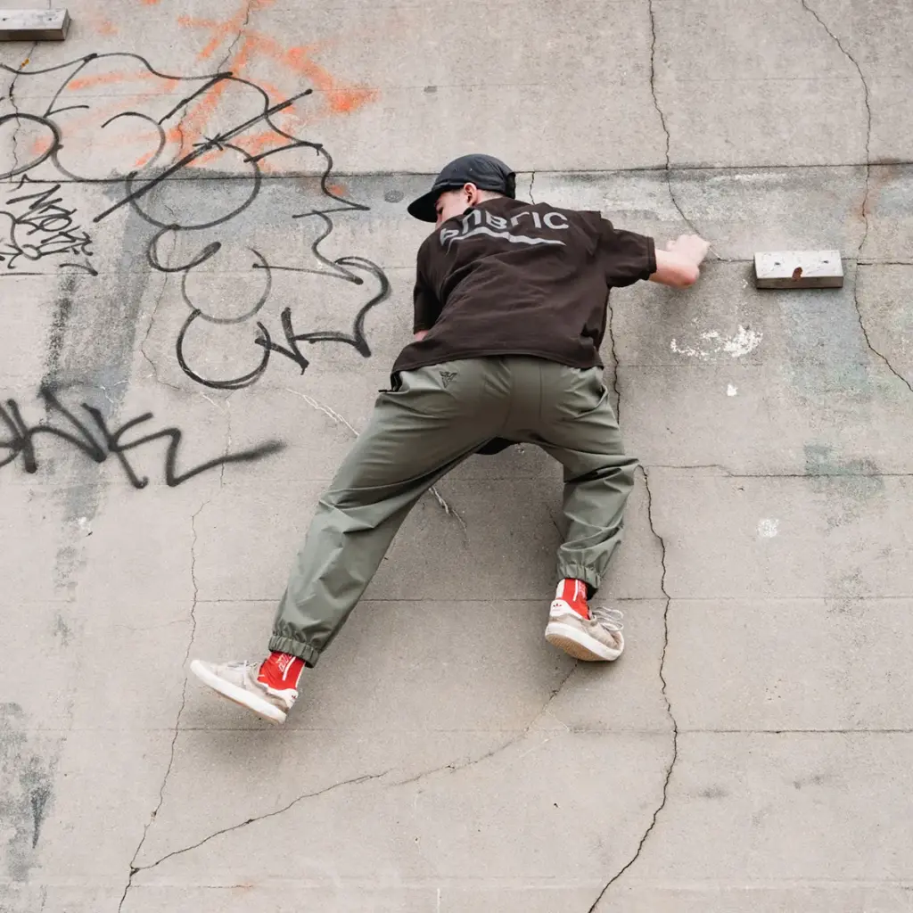 Parkour athlete climbing a graffiti-covered concrete wall.