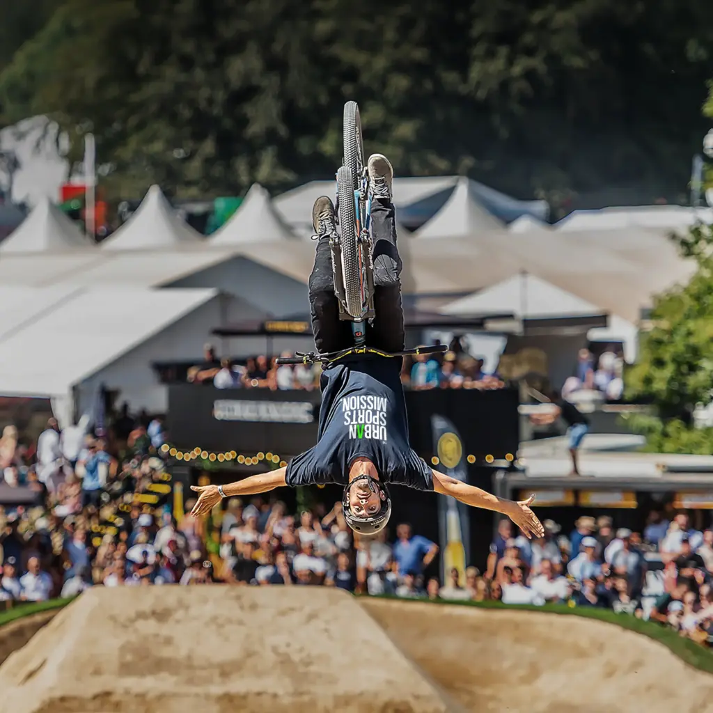 BMX rider performing an inverted aerial trick above a dirt jump, with the words “Welcome to the Mission.